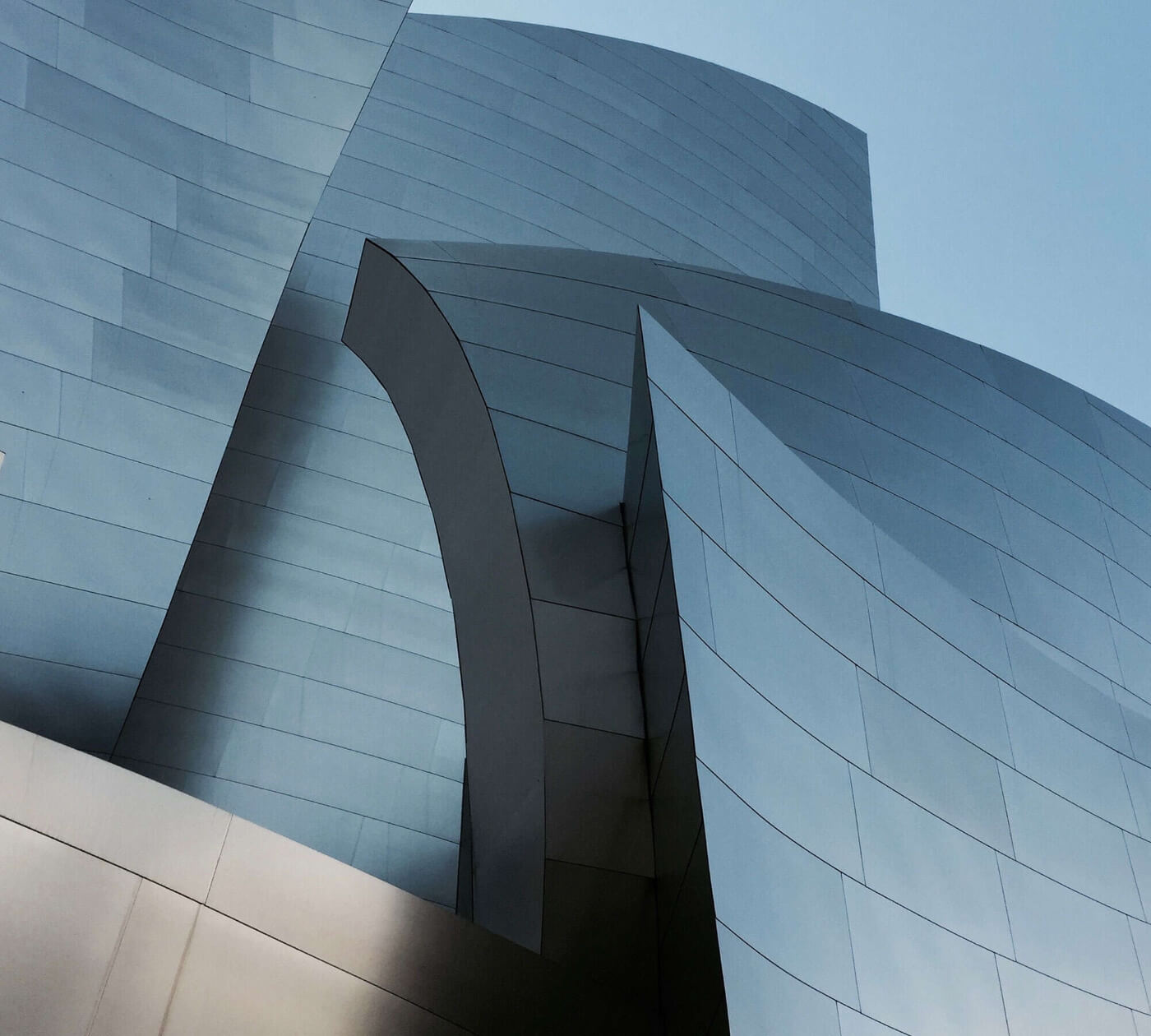 Modern curved metallic building against clear sky.