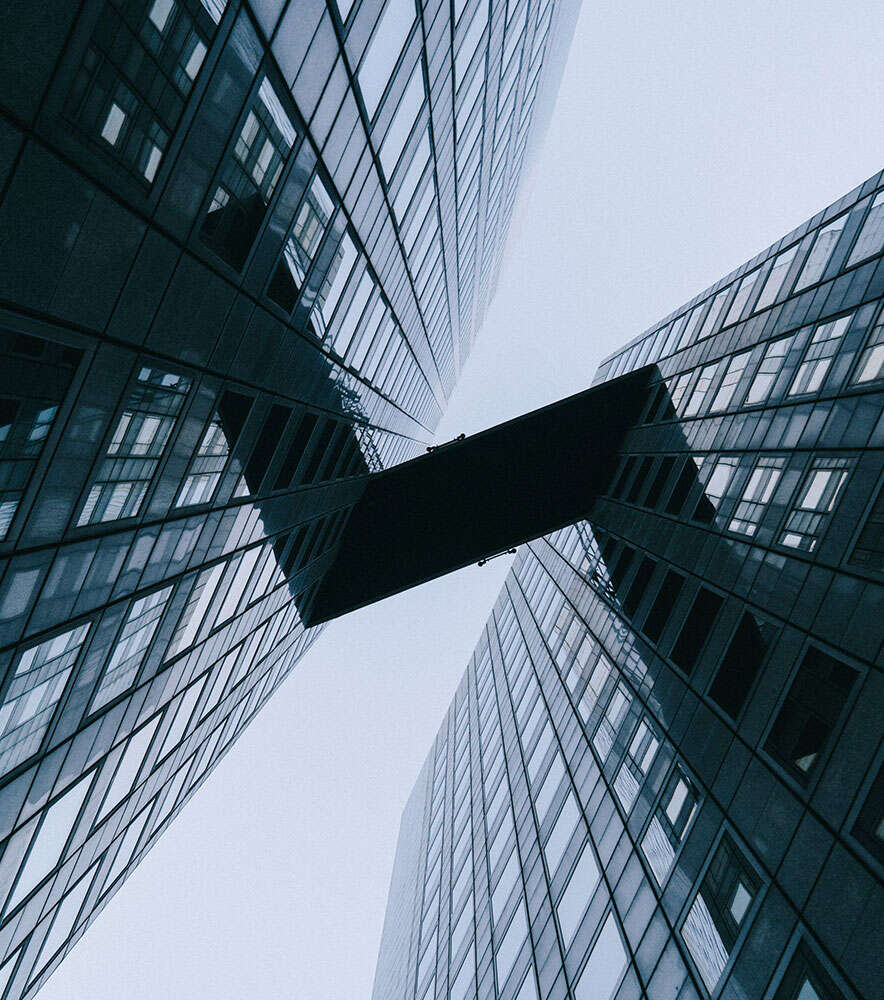 Two modern skyscrapers connected by a skybridge against a clear sky.